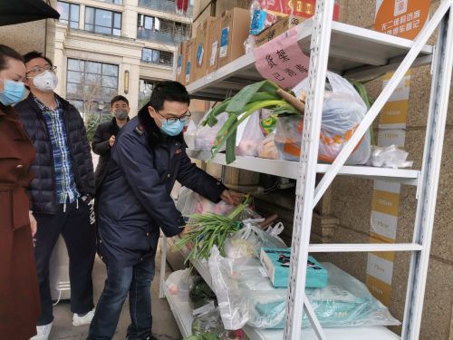 婺城区市场监管局工作人员当起了临时“搬运工”，帮忙把一袋袋物资送到了小区门口已消毒的货架上。田双双 摄