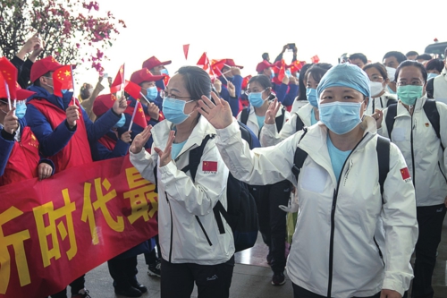  3月17日，天津国家紧急医学救援队队员向志愿者挥手告别。当日，救援队从武汉天河机场撤离前往天津。随着疫情防控形势逐步转好，完成救助任务的各地驰援医疗队将分批离开。新华社