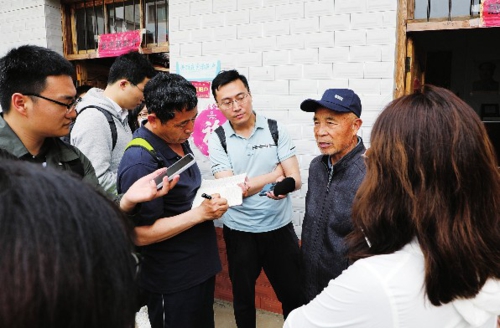  在安徽省阜南县蒙洼蓄洪区郑台孜，73岁老人郑继超正在给记者们讲述洪灾袭来时的今夕对比。张子悦/摄