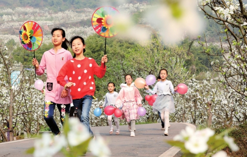  春暖花开时节，人们踏青赏花，享受美好春光。图为3月13日，小朋友在四川省眉山市仁寿县曹家镇东联村梨园里游玩。    新华社