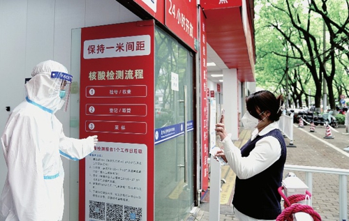  图为市民向上海市闵行区中心医院核酸检测采样点工作人员出示进行核酸采样的随申码。新华社