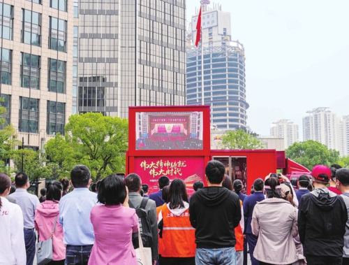  10月16日，中国共产党第二十次全国代表大会在北京人民大会堂开幕。习近平代表第十九届中央委员会向大会作了题为《高举中国特色社会主义伟大旗帜为全面建设社会主义现代化国家而团结奋斗》的报告。报告过程中，全场一次次响起热烈的掌声。报告引发各地干部群众强烈反响和国际社会高度评价。图为10月16日，在上海中共一大纪念馆前，工作人员、志愿者和观众在收看中国共产党第二十次全国代表大会开幕会。新华社