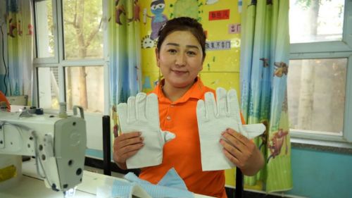 古渔村村民阿依古丽海白布展示完工的手套