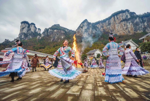  刚刚过去的元旦假期，我国各地消费市场人气渐旺，暖意渐浓。图为游客在贵州省黔西市新仁苗族乡化屋村和苗族同胞一起围着篝火跳舞。 新华社