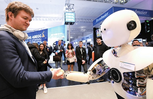  日前，在德国汉诺威工业博览会上，一名观众与智能机器人握手。新华社