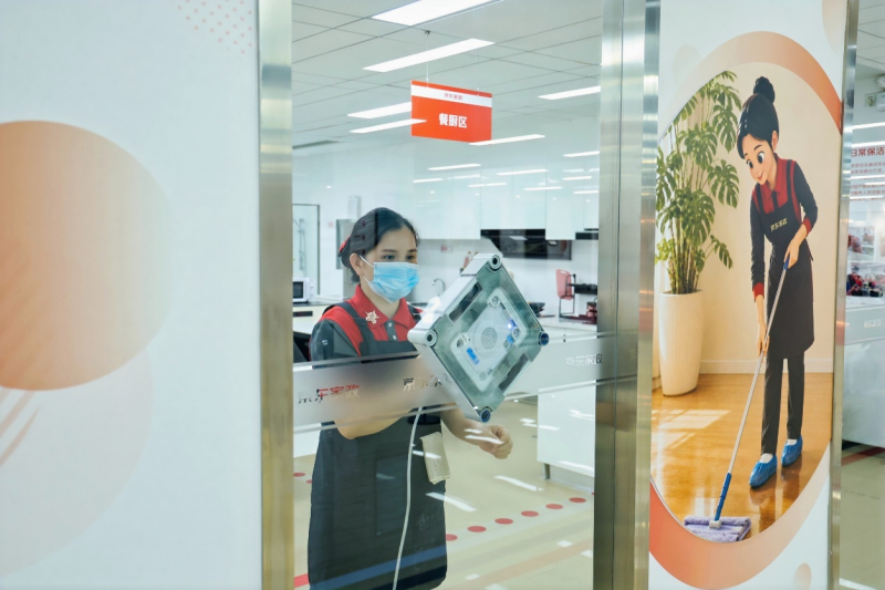 保洁师在玻璃清洗中使用擦窗机器人协同打扫
